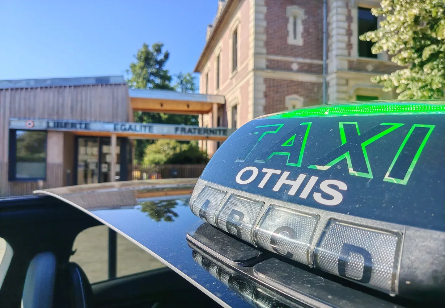 Lumineux de toit TAXI OTHIS allumé, mairie d'Othis en arrière-plan